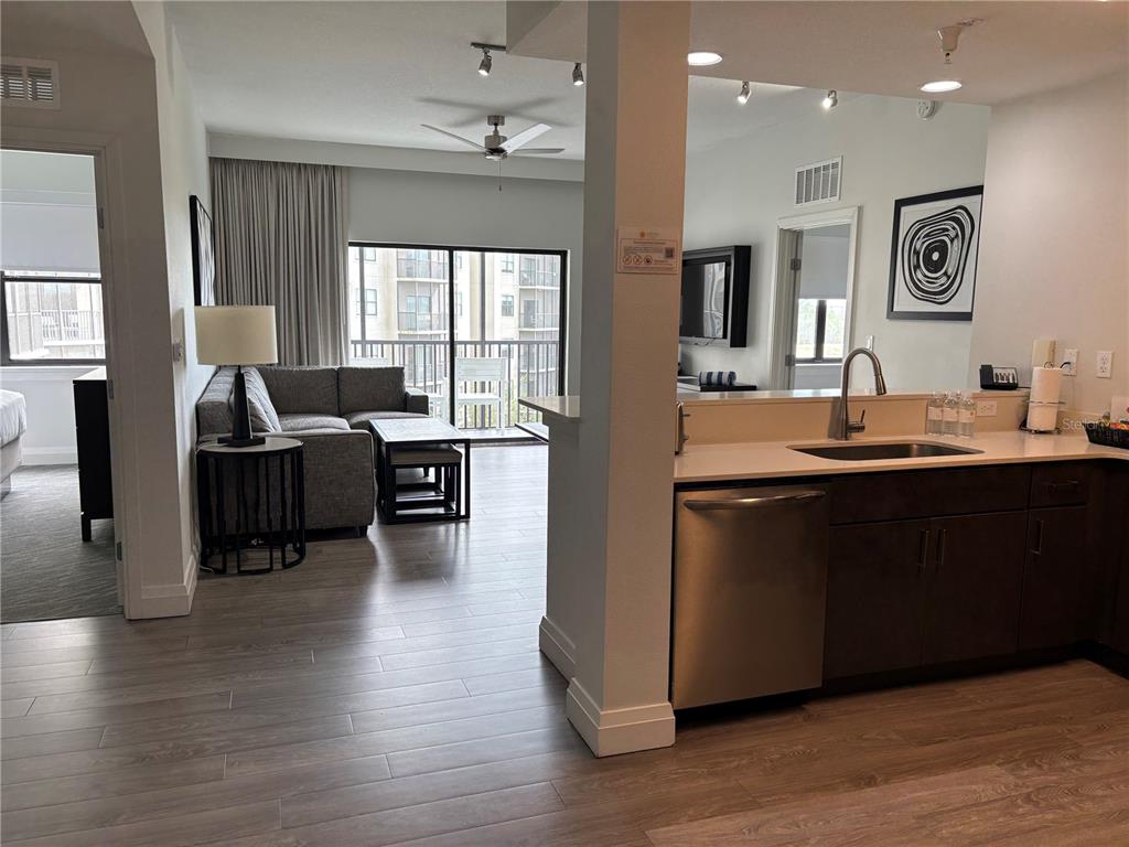 A kitchen with dark cabinets and stainless steel appliances overlooks a living area with balcony access — 14501 GROVE RESORT AVENUE UNIT 3534, WINTER GARDEN, FL