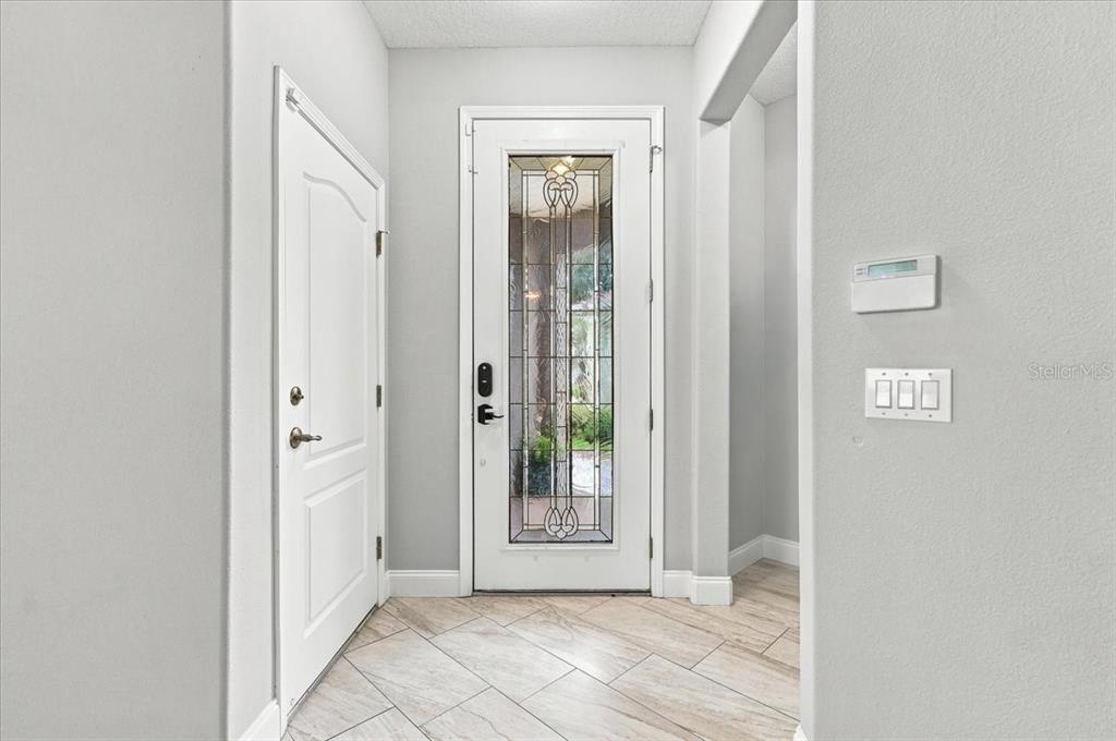 An entryway features a white front door with a decorative glass insert and tiled flooring — 10908 SUBTLE TRAIL DRIVE, RIVERVIEW, FL