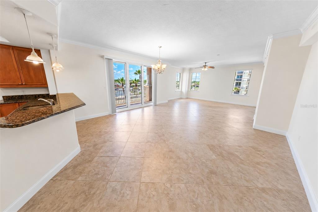 An open-concept dining and living area features tile flooring, a kitchen island, and balcony access — 2515 S ATLANTIC AVENUE UNIT 301, DAYTONA BEACH, FL