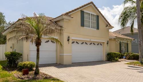 A two-story house with a beige stucco exterior, a tiled roof, and a paved driveway — 65 CALLIOPE STREET, OCOEE, FL