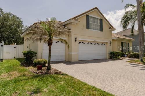 A two-story house with a beige exterior, a two-car garage, and a paved driveway — 65 CALLIOPE STREET, OCOEE, FL