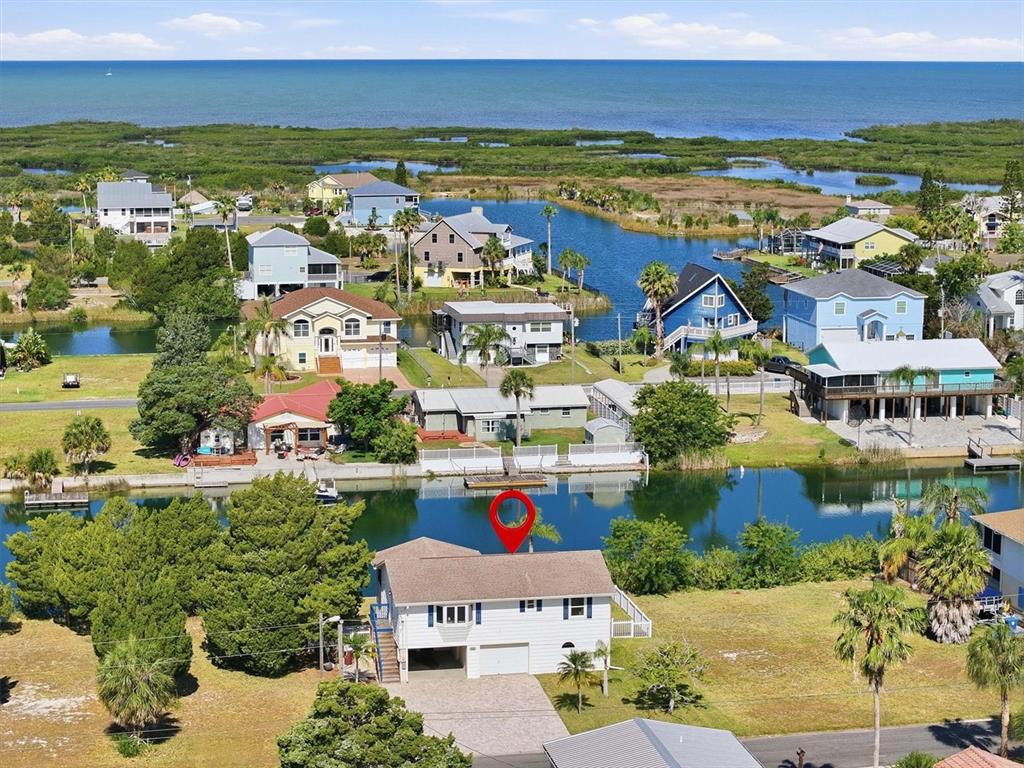An aerial view shows a house with a red pin in a waterfront neighborhood at sunset — 3347 OLEANDER DRIVE, HERNANDO BEACH, FL