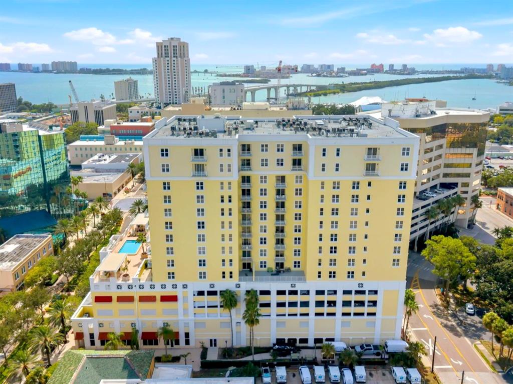 An aerial view shows a yellow multi-story building with a pool and parking garage — 628 CLEVELAND STREET UNIT 1507, CLEARWATER, FL