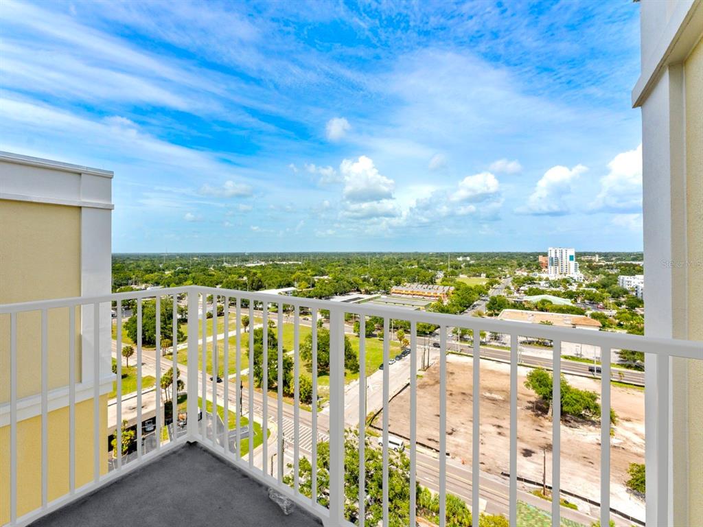 A high-angle view from a balcony overlooking a suburban landscape with trees and buildings — 628 CLEVELAND STREET UNIT 1507, CLEARWATER, FL