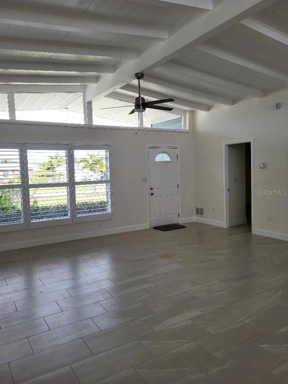 A bright living room features white vaulted ceilings with exposed beams and light tile flooring — 828 BLUE HERON BOULEVARD, RUSKIN, FL