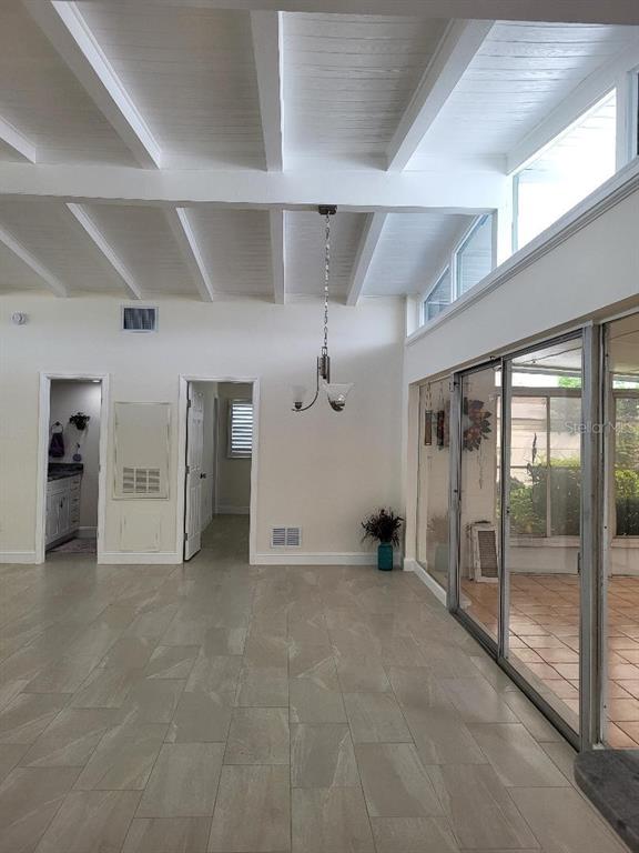 A bright room features a vaulted beamed ceiling, tile flooring, and large sliding glass doors — 828 BLUE HERON BOULEVARD, RUSKIN, FL