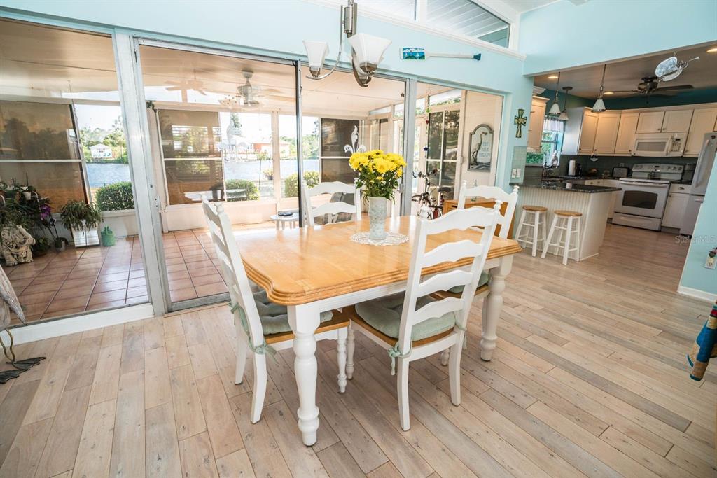 A dining area with a wooden table and white chairs overlooks a screened-in patio — 828 BLUE HERON BOULEVARD, RUSKIN, FL