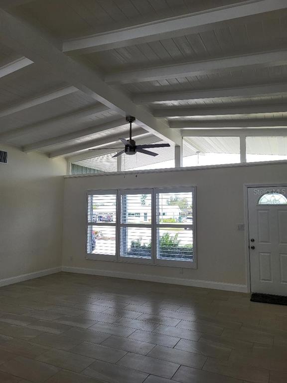 A living room features a vaulted beamed ceiling, tile flooring, and large windows — 828 BLUE HERON BOULEVARD, RUSKIN, FL
