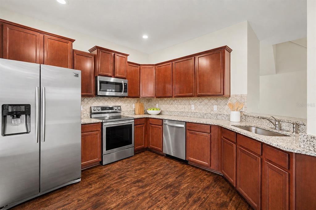 A kitchen features cherry wood cabinets, stainless steel appliances, and granite countertops — 5520 KINGLETHILL DRIVE, LITHIA, FL