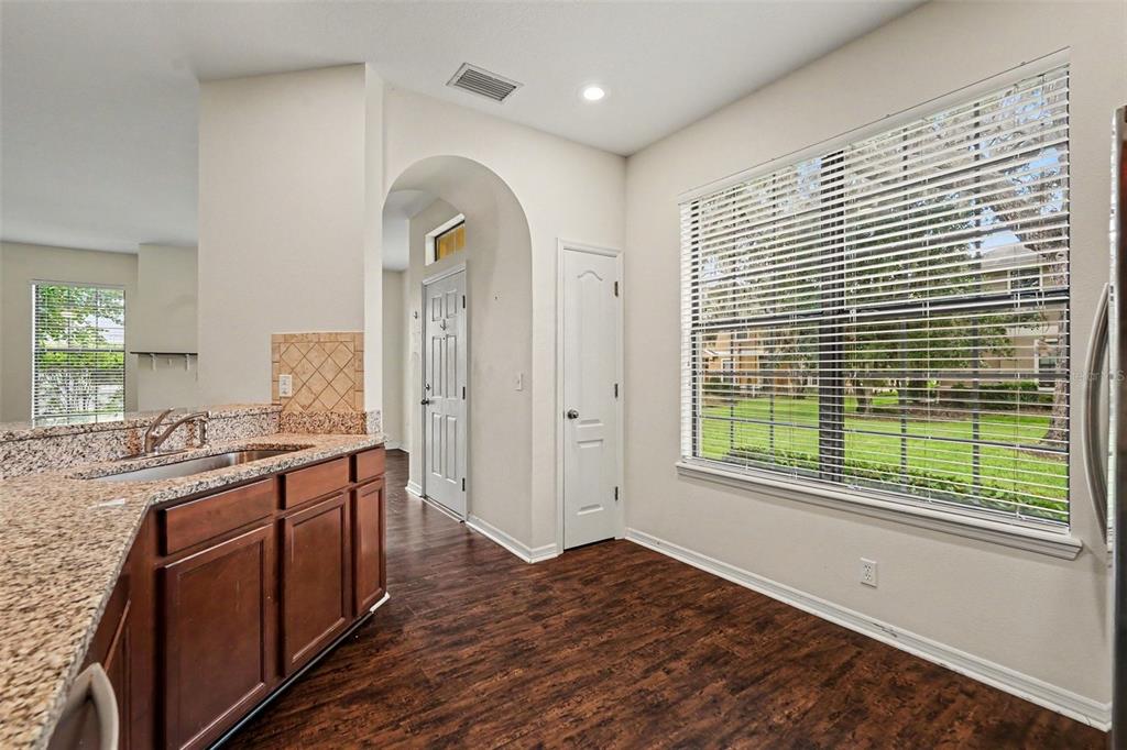 A kitchen with dark wood cabinets, granite countertops, and a large window overlooking a lawn — 5520 KINGLETHILL DRIVE, LITHIA, FL