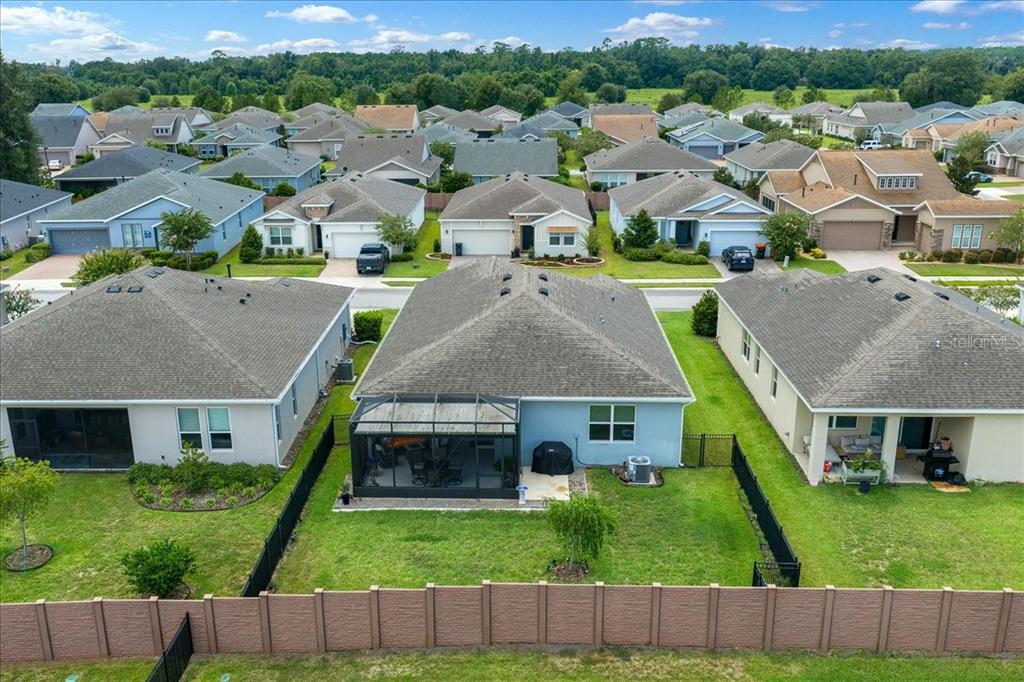 An aerial view shows the backyards and rear exteriors of several suburban houses with fences — 4355 NW 55TH TERRACE, OCALA, FL