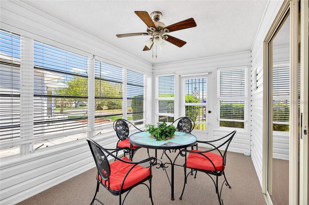A sunroom features a round table with four chairs, a ceiling fan, and large windows — 932 CHULA CT, LADY LAKE, FL