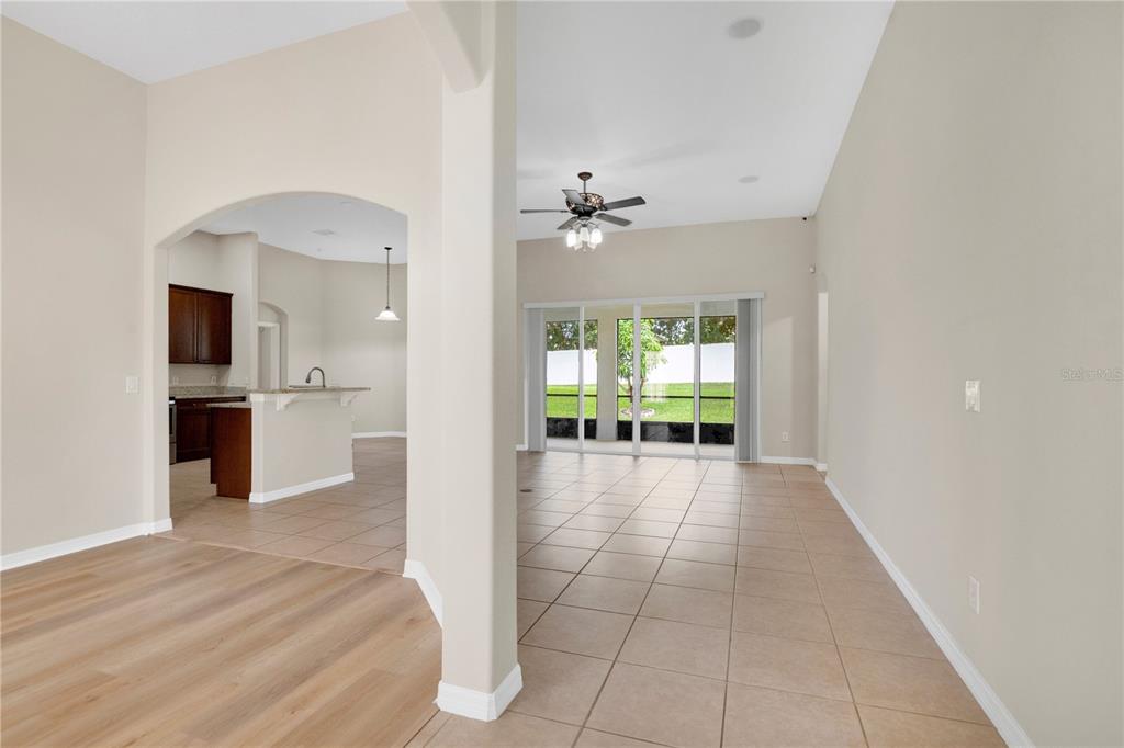 An open-concept living area with tile flooring, a ceiling fan, and sliding glass patio doors — 253 BEACON POINTE DRIVE, OCOEE, FL