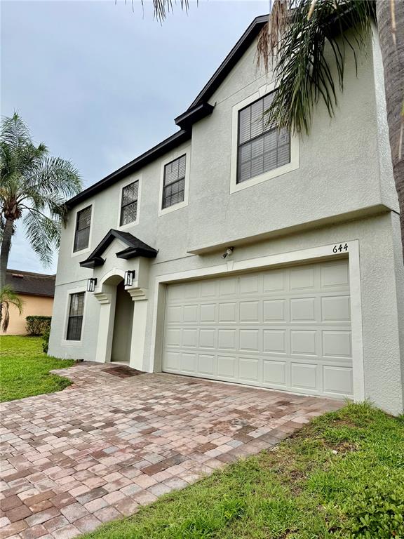 A two-story house exterior features a paved driveway, a garage, and a covered entryway — 644 SAVANNAH PRESERVE LOOP, DAVENPORT, FL