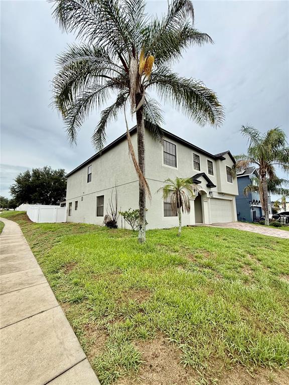 A two-story house with light-colored stucco siding and a palm tree in the front yard — 644 SAVANNAH PRESERVE LOOP, DAVENPORT, FL