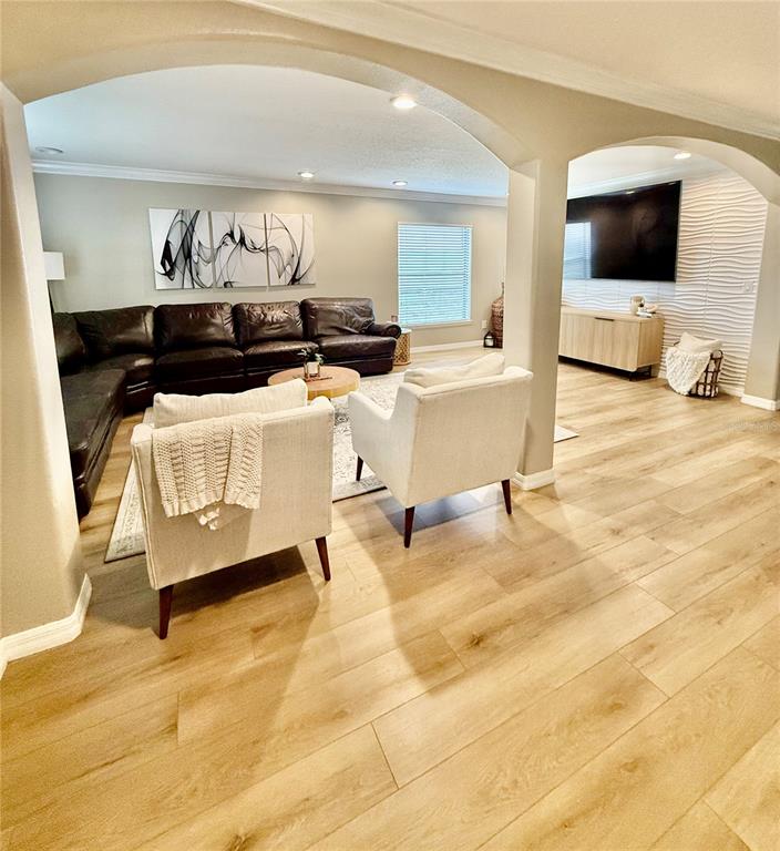 A living room features a dark leather sectional, two white armchairs, and light wood flooring — 644 SAVANNAH PRESERVE LOOP, DAVENPORT, FL