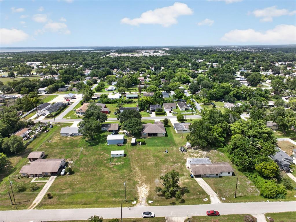 An aerial view shows a residential neighborhood with several houses, large grassy lots, and trees — 212 15TH AVENUE, OCOEE, FL