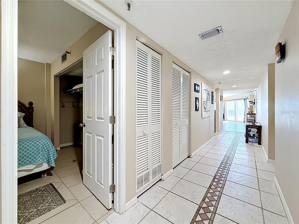 A tiled hallway leads past two louvered closet doors toward a bright living area — 18400 GULF BOULEVARD UNIT 1108, INDIAN SHORES, FL