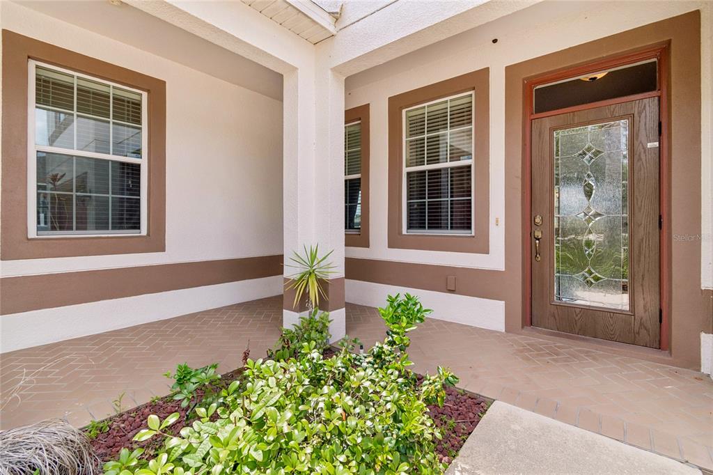 A living room features green paneled walls, a patterned rug, and sliding doors to a patio — 13344 GRAHAM YARDEN, RIVERVIEW, FL