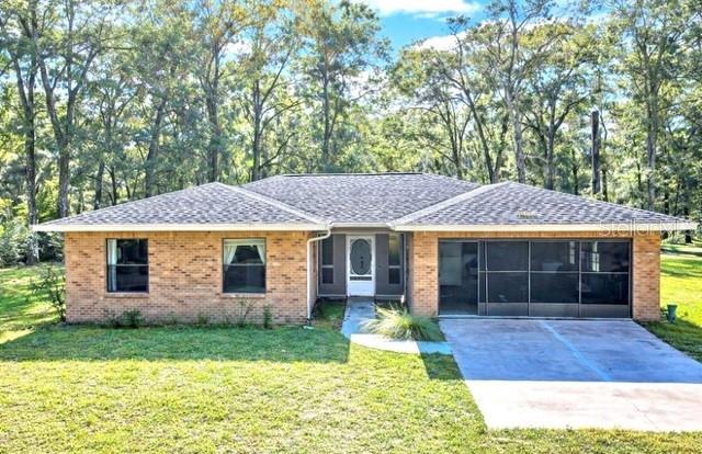 A single-story brick house with a two-car garage sits on a wooded, grassy lot — 26250 BLACKJACK STREET, BROOKSVILLE, FL