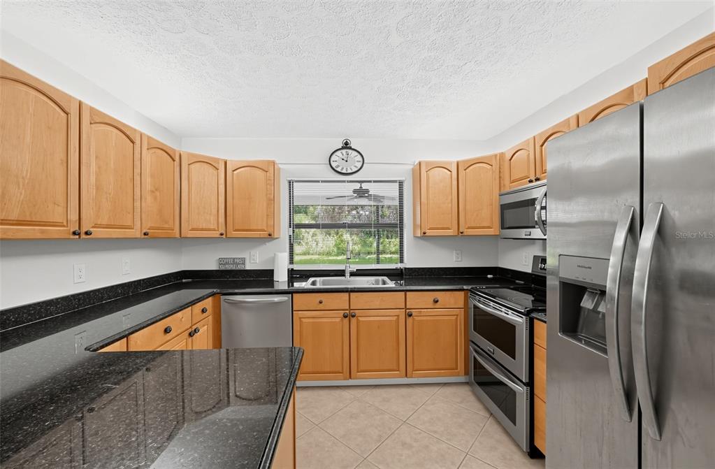 A kitchen with light wood cabinets, black granite countertops, and stainless steel appliances — 3951 SW CHERIBON STREET, PORT ST LUCIE, FL