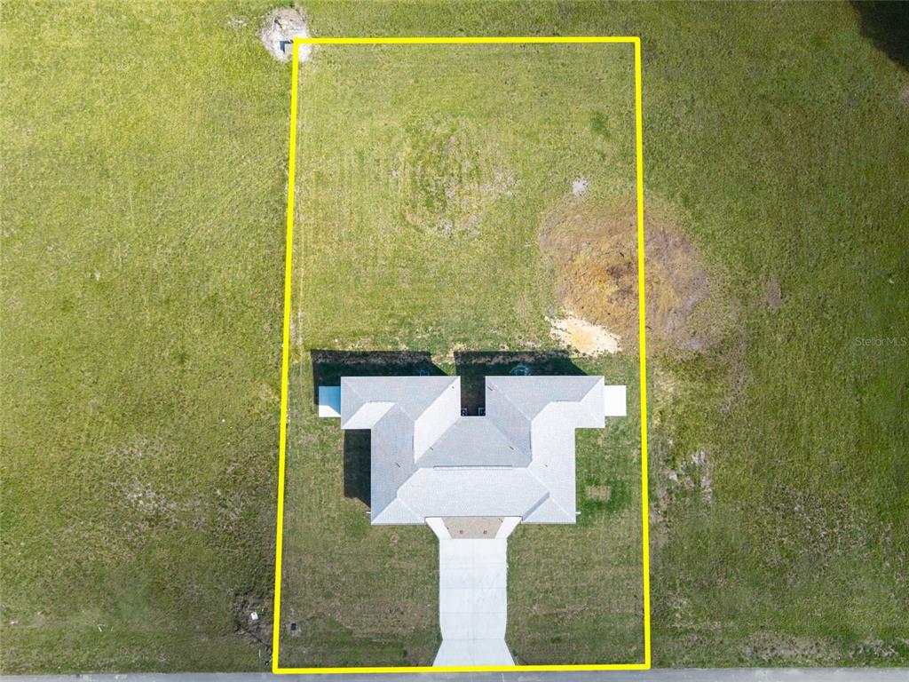 An aerial view of the rear exterior of a single-story duplex with a grassy yard — 6301 CANDLER TERRACE, SEBRING, FL
