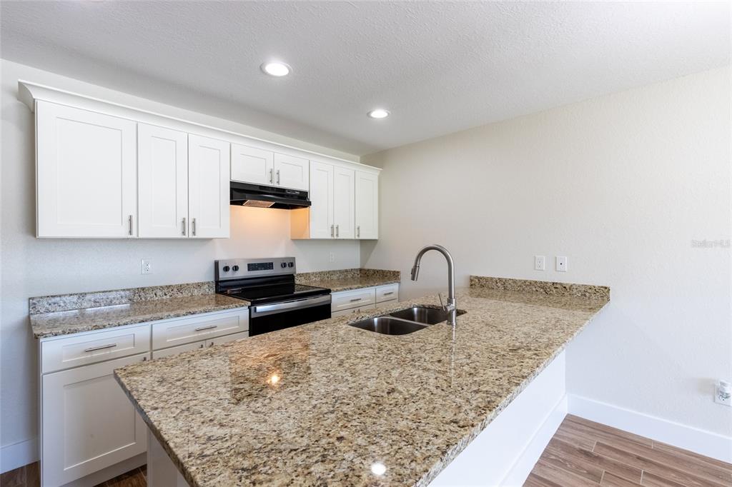 An empty room with wood-look flooring, a ceiling fan, a window, and a white door — 6301 CANDLER TERRACE, SEBRING, FL