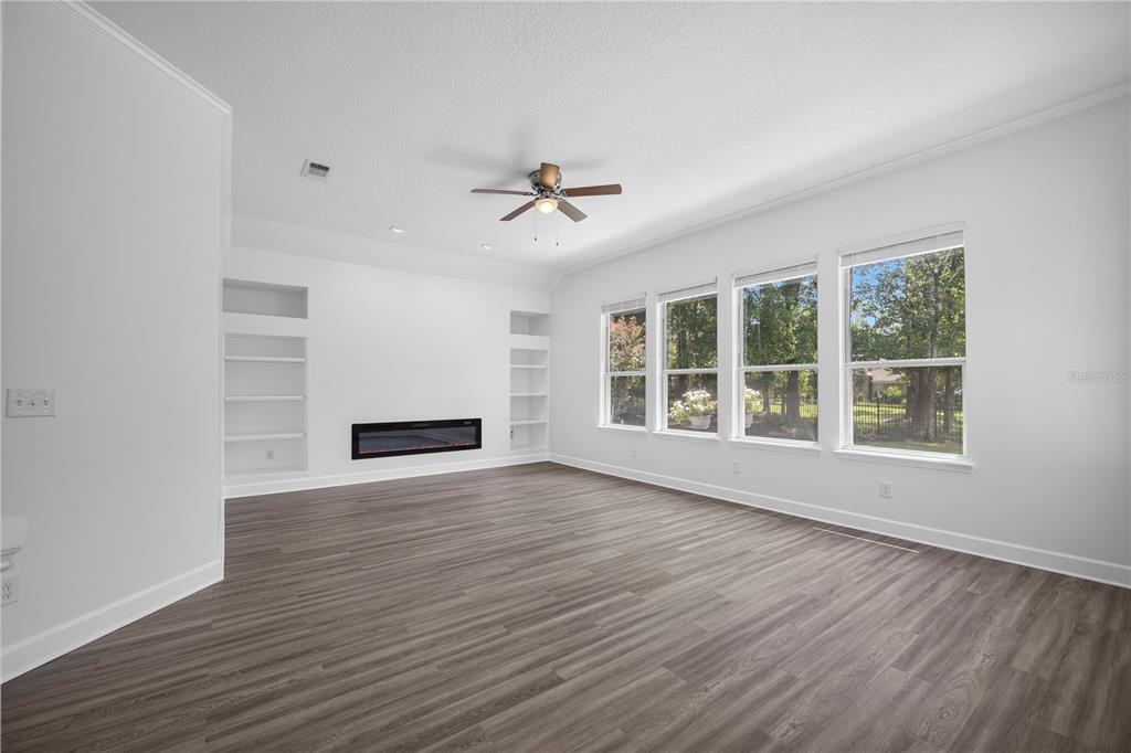 A living room with light gray walls, wood-look flooring, a fireplace, and large windows — 656 WYNDHAM COURT, ORANGE PARK, FL