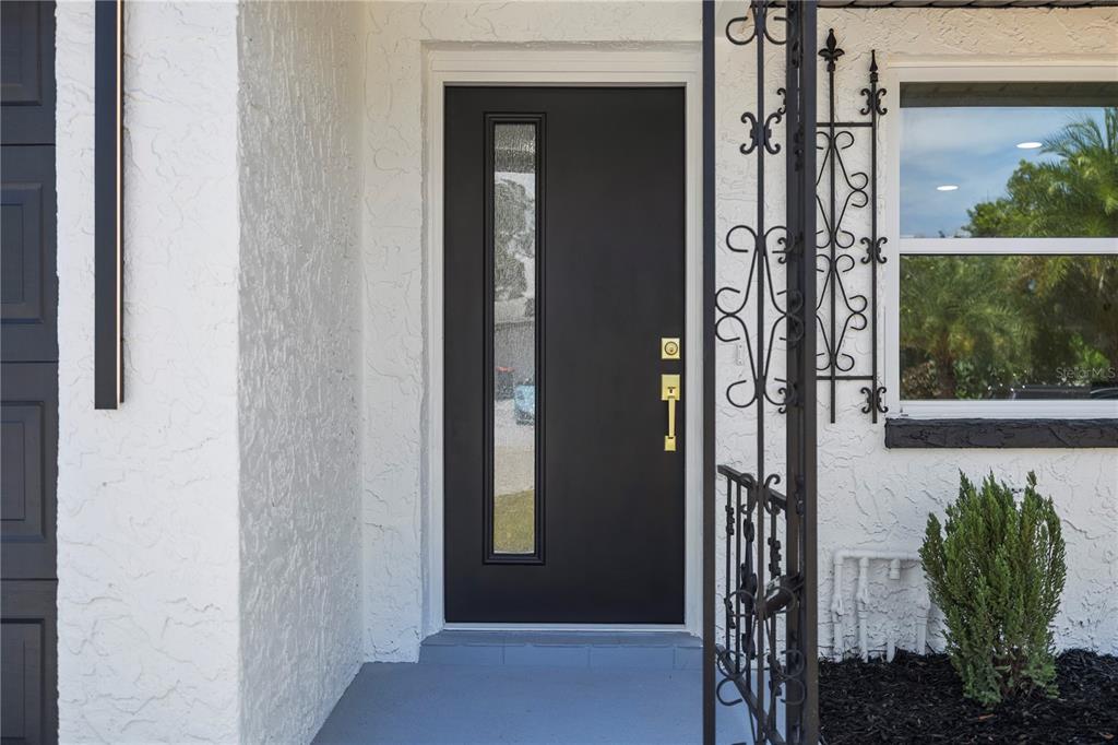A black front door with a vertical glass panel sits on a white stucco exterior — 6444 JUNIPER ROAD, PORT RICHEY, FL