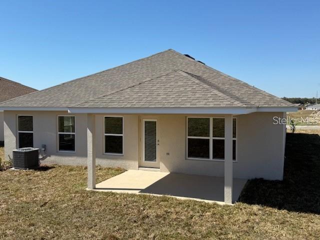 The back exterior of a single-story house features a covered concrete patio and tan siding — 4404 SW 92ND PLACE ROAD, OCALA, FL