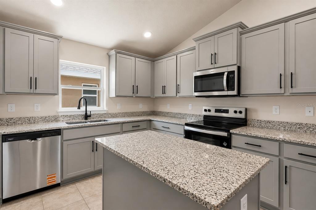 A kitchen with gray cabinets, granite countertops, stainless steel appliances, and a central island — 1667 ANN ROSE WAY, LEESBURG, FL