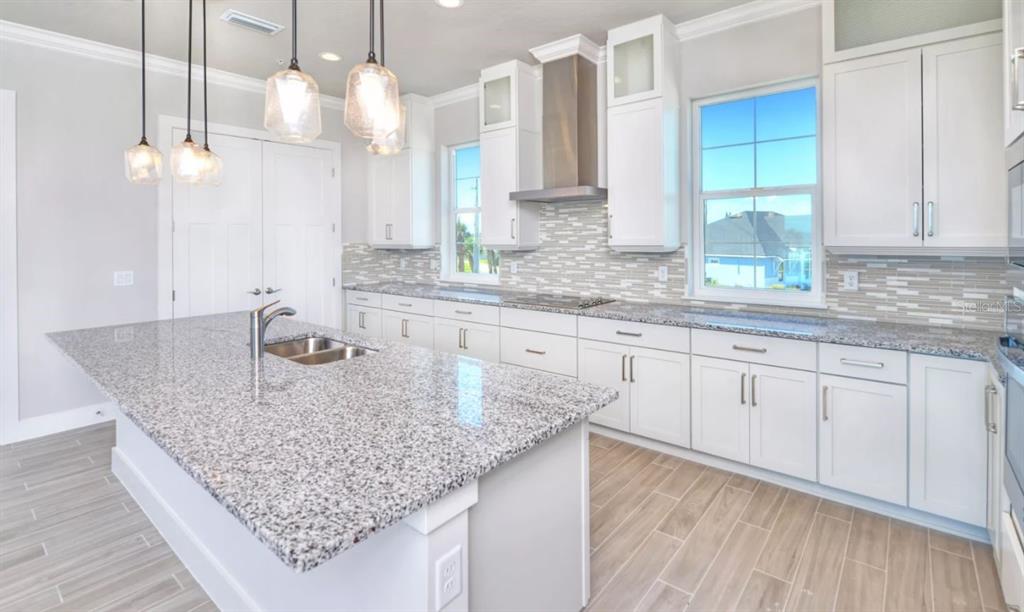 A modern kitchen features white cabinets, granite countertops, a large island, and stainless steel appliances — 23 MARDEN DRIVE UNIT 51, ORMOND BEACH, FL