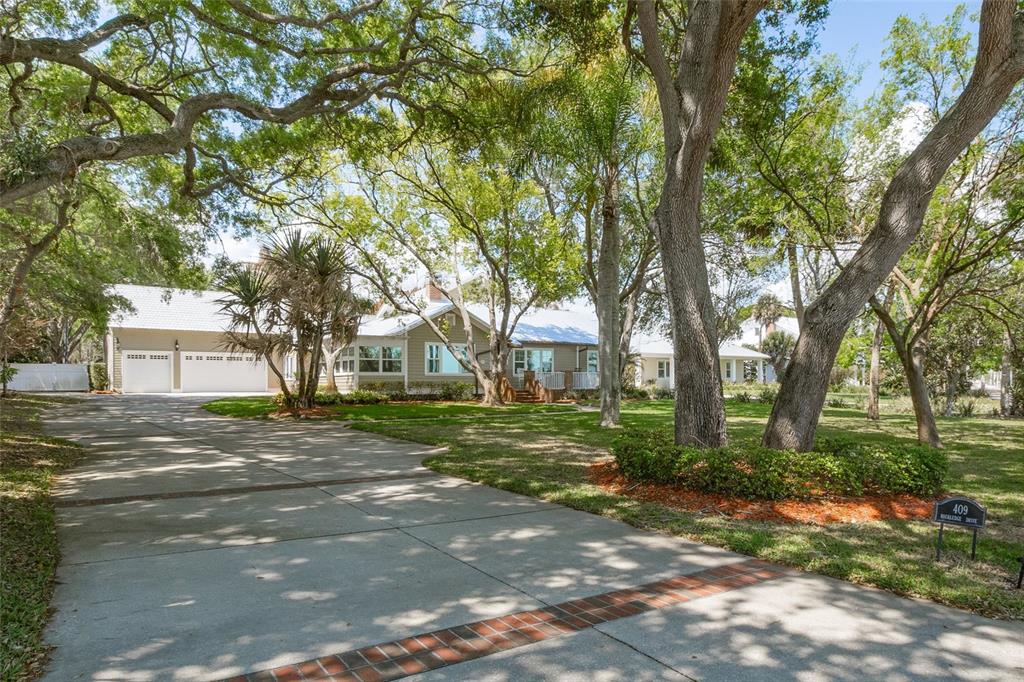 A long concrete driveway leads to a single-story house surrounded by large, mature trees — 409 ROCKLEDGE DRIVE, ROCKLEDGE, FL