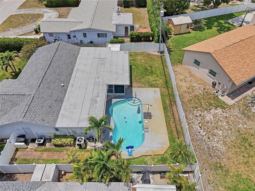 An aerial view shows a house with a swimming pool and patio in the backyard — 14161 HETRICK CIRCLE N, LARGO, FL