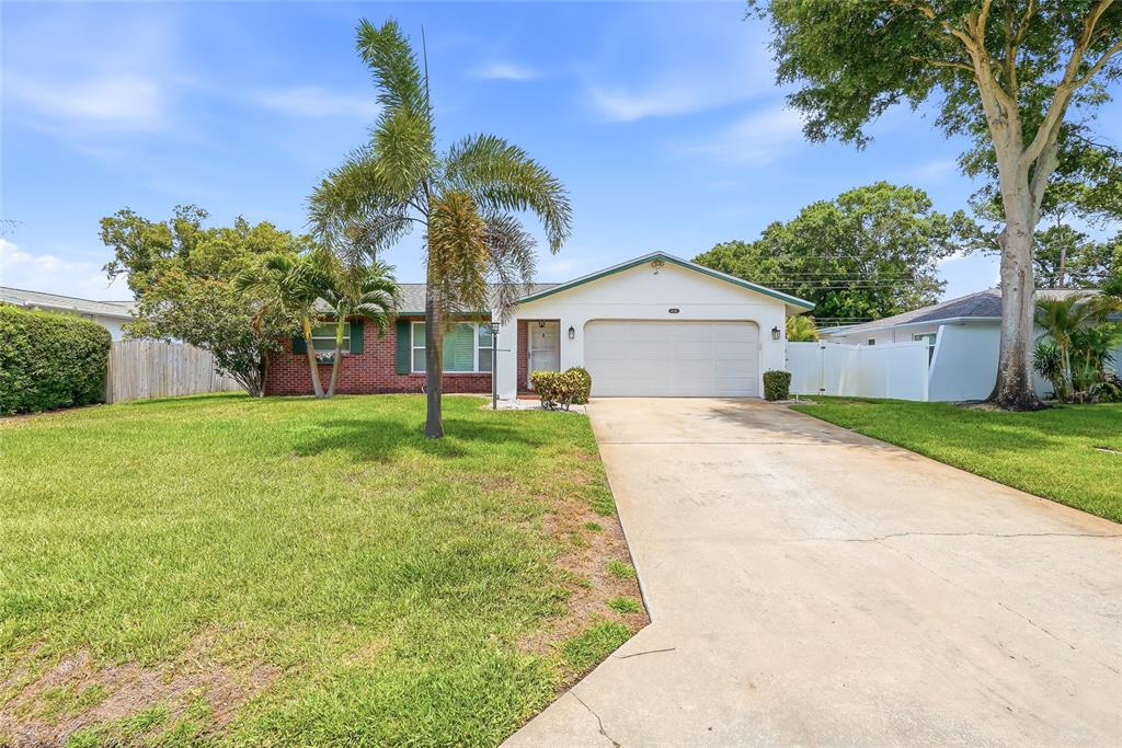 A single-story brick and white house with a concrete driveway and a palm tree — 14161 HETRICK CIRCLE N, LARGO, FL