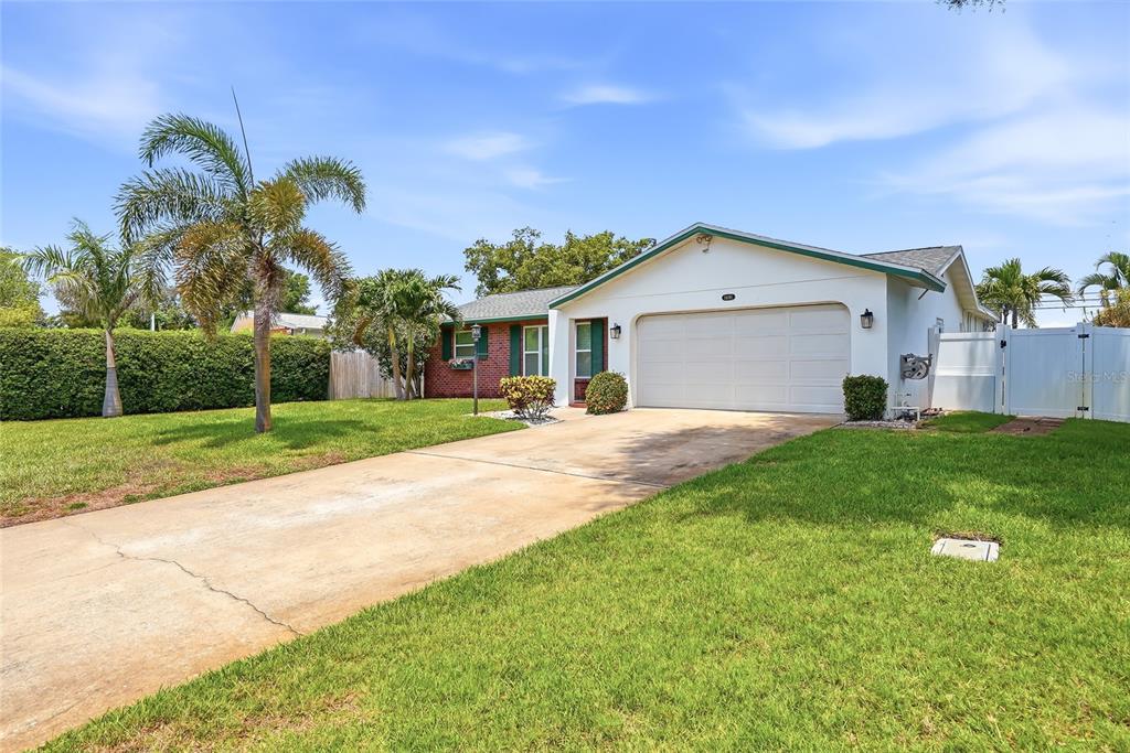 A single-story house with a white garage, brick accents, and palm trees in the yard — 14161 HETRICK CIRCLE N, LARGO, FL
