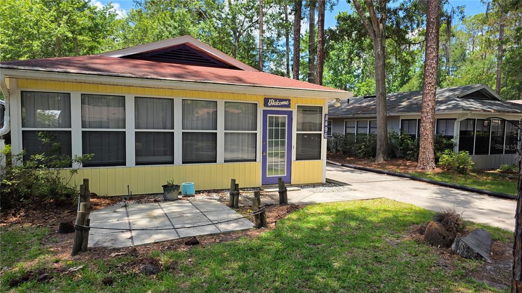 The exterior of a yellow house with a brown roof is surrounded by trees — 8496 NW 38TH TERRACE, GAINESVILLE, FL
