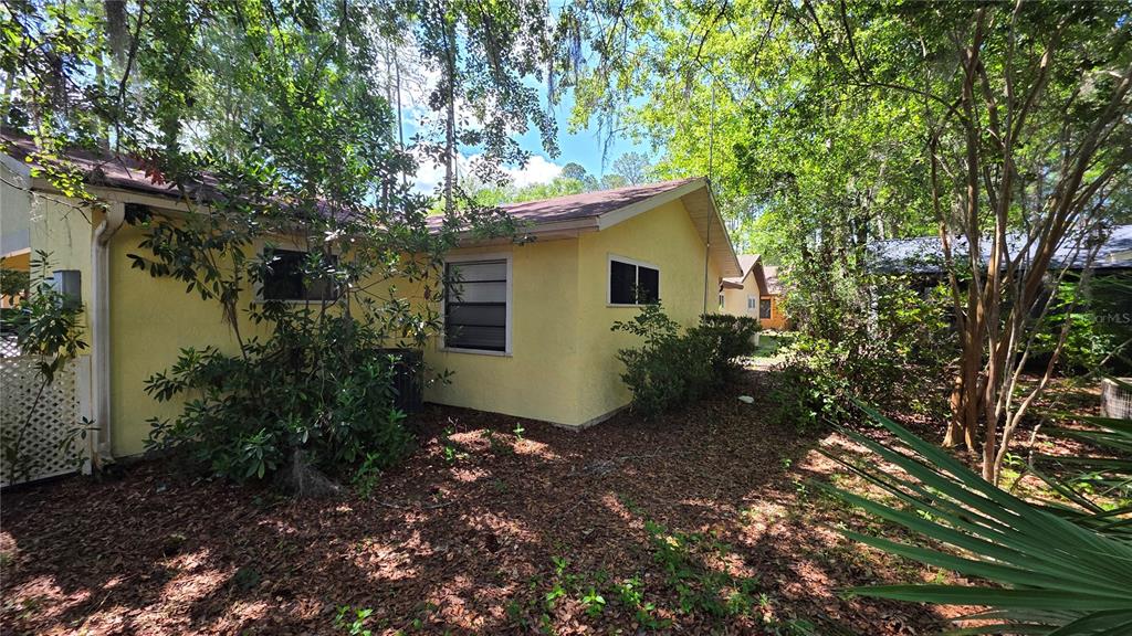 A sunroom features light green paneled walls, wood-look flooring, a ceiling fan, and large windows — 8496 NW 38TH TERRACE, GAINESVILLE, FL