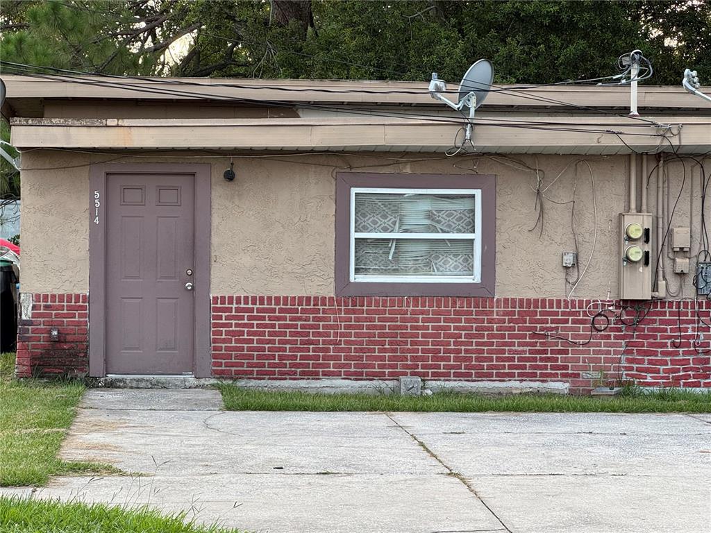 The exterior of a single-story building features a brown door, a window, and brick siding — 5514 S RIO GRANDE AVENUE, ORLANDO, FL