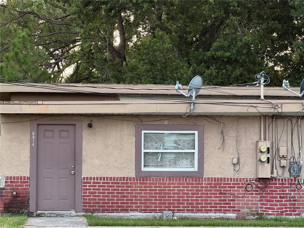 The exterior of a single-story building features a brown door, a window, and brick siding — 5514 S RIO GRANDE AVENUE, ORLANDO, FL