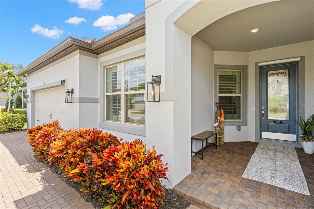 A front entrance features a blue door, a brick walkway, and colorful croton shrubs — 1528 FOREST GLEN COURT, PALM HARBOR, FL