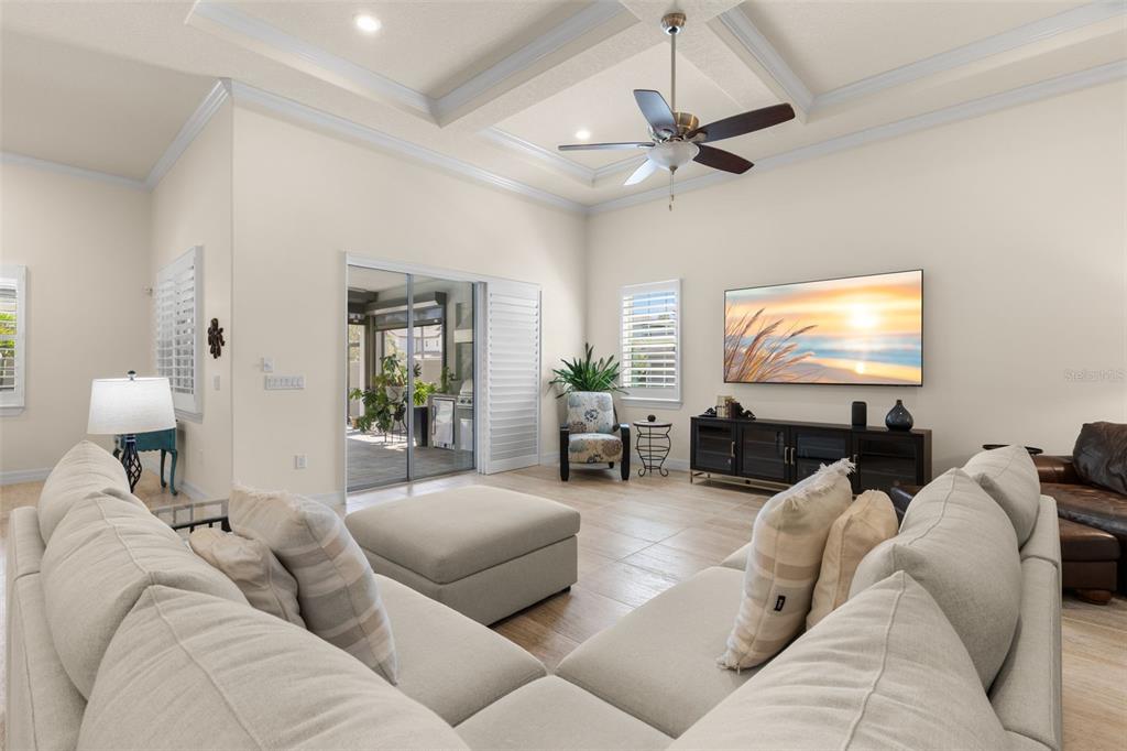 A living room features a tray ceiling, a large sectional sofa, and a sliding glass door — 1528 FOREST GLEN COURT, PALM HARBOR, FL