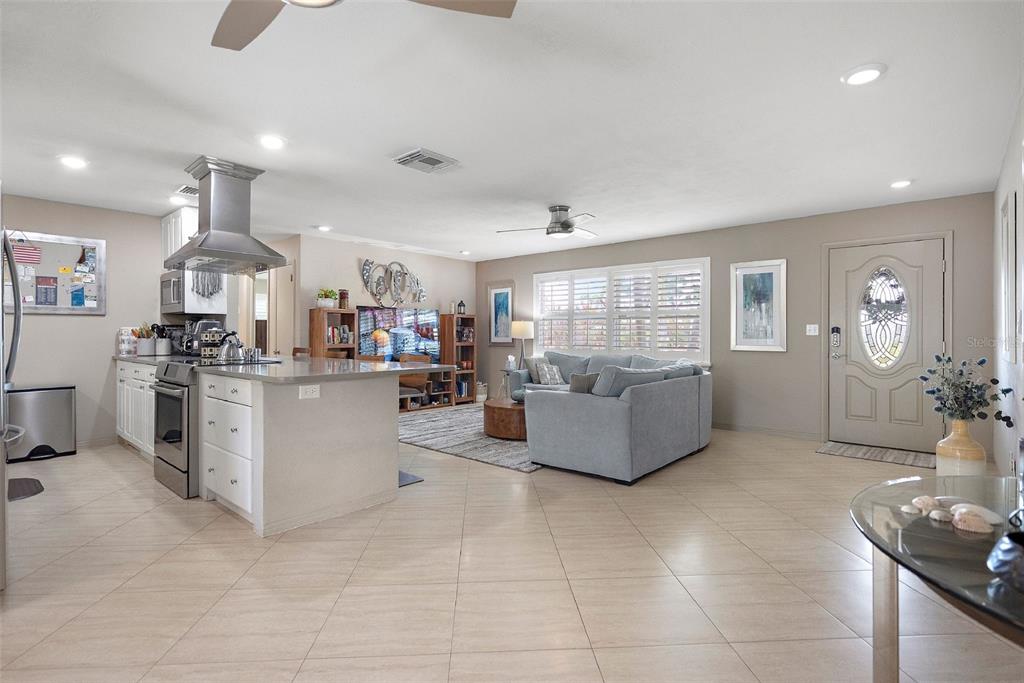 An open-concept kitchen and living area features tile flooring, a center island, and neutral walls — 101 MADONNA BOULEVARD, TIERRA VERDE, FL