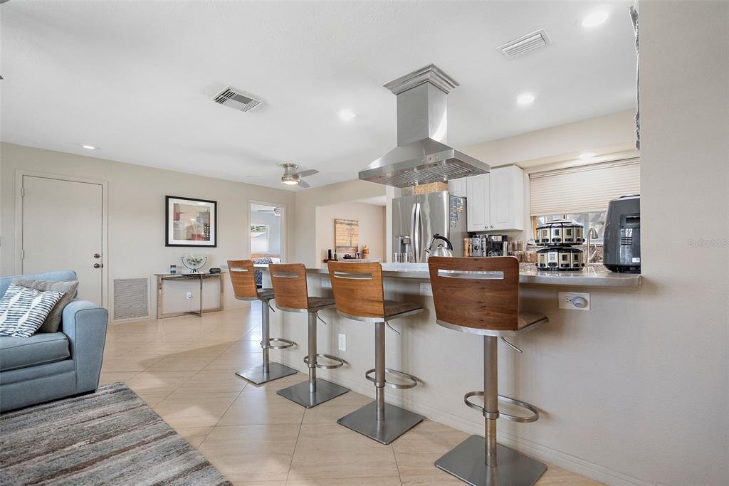 A kitchen with a breakfast bar, four wooden stools, and a stainless steel range hood — 101 MADONNA BOULEVARD, TIERRA VERDE, FL