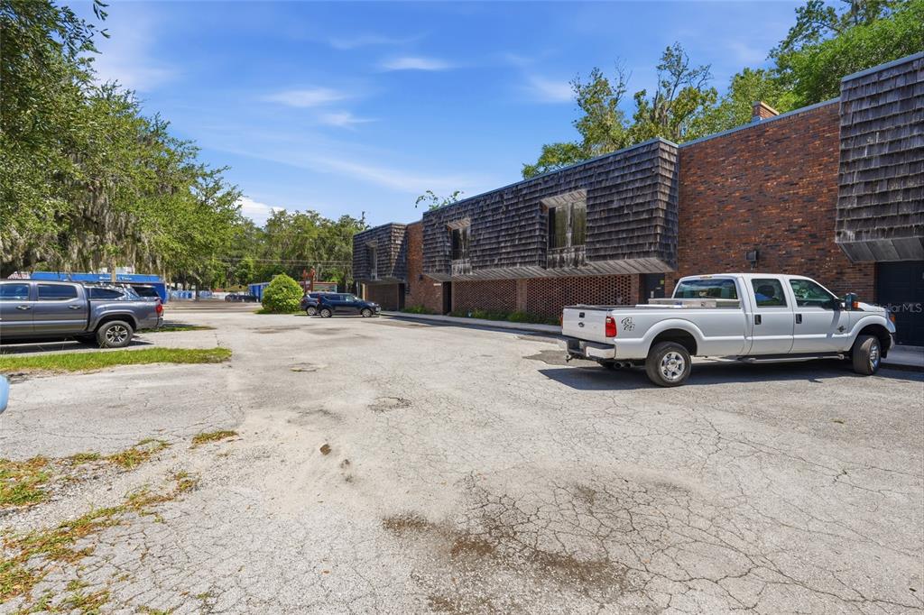 A brick building with shingled upper levels sits beside a parking lot with two trucks — 711 NW 23RD AVENUE UNIT 3, GAINESVILLE, FL