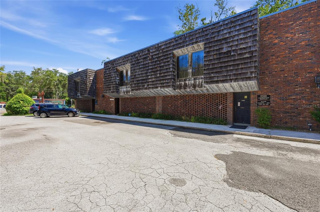 A two-story commercial building with a brick base, wood-shingled upper level, and a parking lot — 711 NW 23RD AVENUE UNIT 3, GAINESVILLE, FL