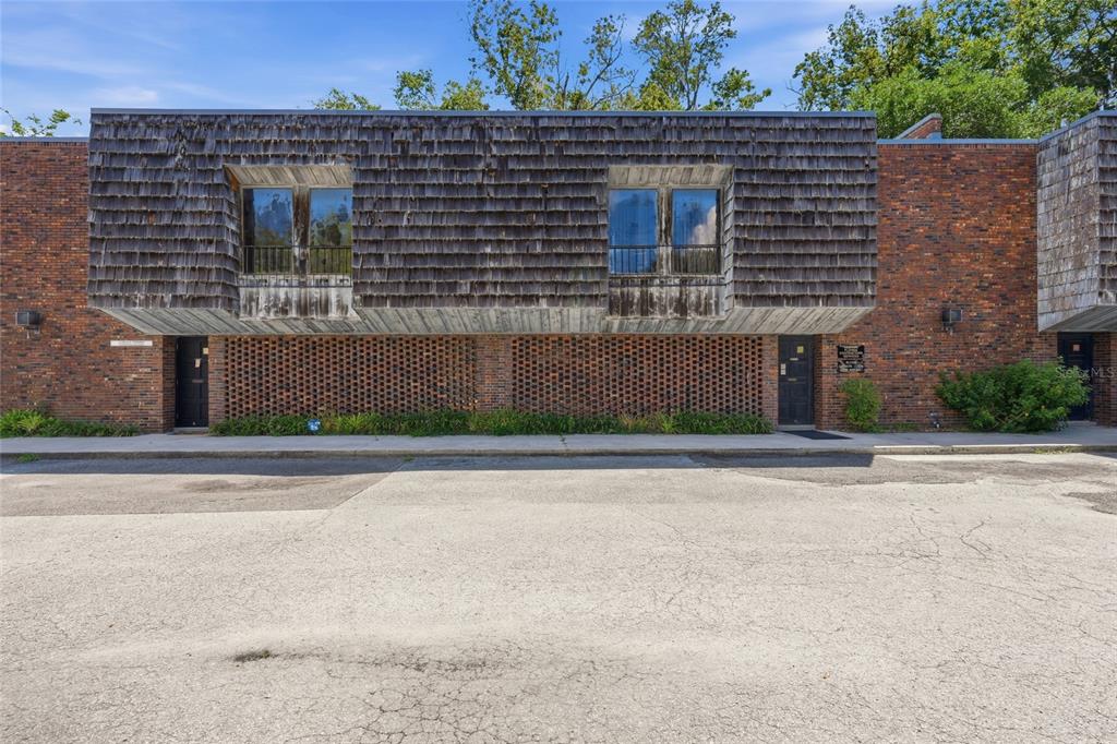 A two-story brick building features a cantilevered upper level with weathered wood shake siding — 711 NW 23RD AVENUE UNIT 3, GAINESVILLE, FL