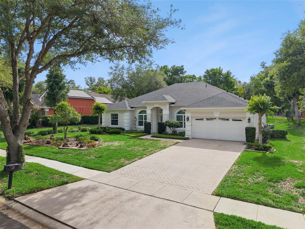 A single-story house with a white stucco exterior, arched windows, and a two-car garage — 156 SEVILLE CHASE DRIVE, WINTER SPRINGS, FL