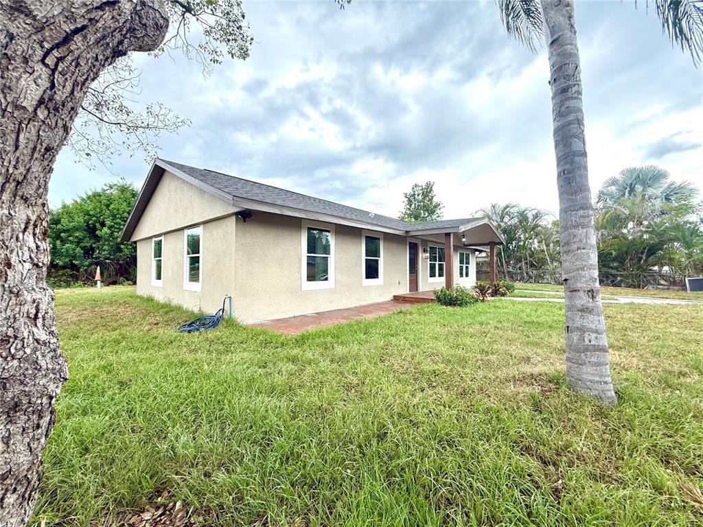 A single-story house with a stucco exterior and a covered entryway sits on a lawn — 1427 MURILLO LOOP, RUSKIN, FL