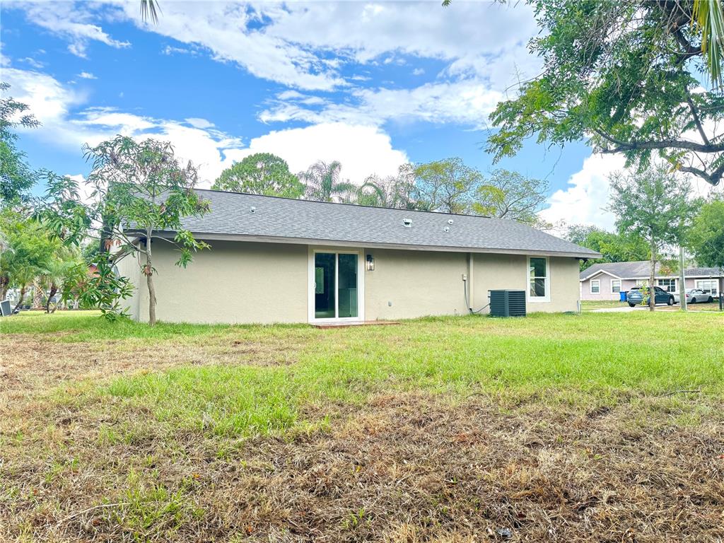 The exterior of a single-story house features a tan stucco facade and a sliding door — 1427 MURILLO LOOP, RUSKIN, FL